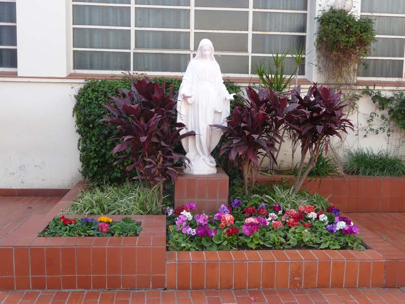 Imagen de la Virgen en un cantero con flores